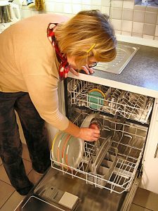  Eine Frau räumt Geschirr in eine Spülmaschine ein.